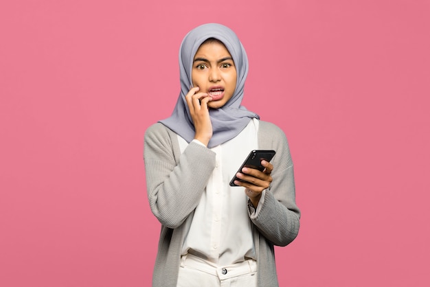 Retrato de uma jovem mulher asiática com medo e segurando o telefone celular