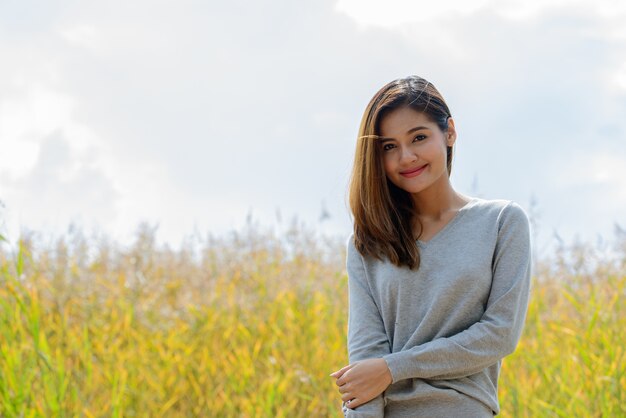 Retrato de uma jovem mulher asiática linda relaxando nos campos de grama alta na natureza