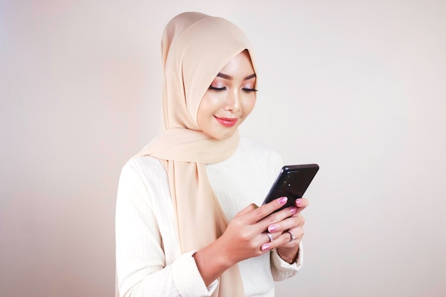 Retrato de uma jovem mulher asiática muçulmana alegre sorrindo enquanto olhava para seu celular