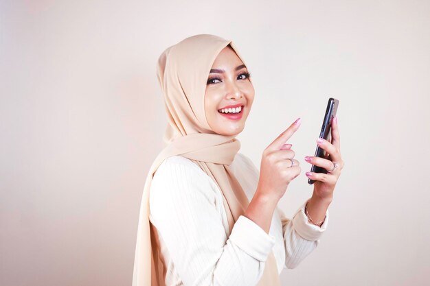 Retrato de uma jovem mulher asiática muçulmana alegre sorrindo enquanto olhava para seu celular