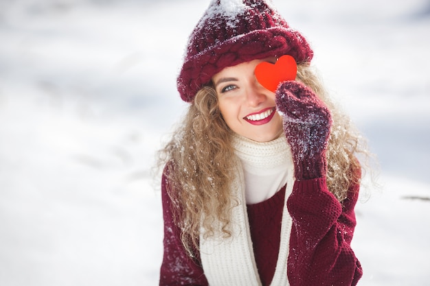 Retrato de uma jovem mulher atraente ao ar livre no inverno, mostrando o coração de papel