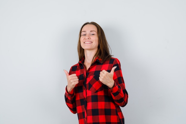 Retrato de uma jovem mulher bonita apontando para direções opostas em uma camisa casual e olhando para a frente alegre