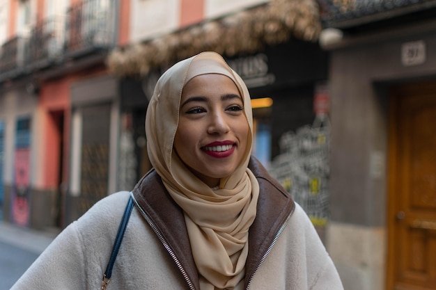 Retrato de uma jovem mulher bonita árabe no tradicional lenço sorrindo alegremente para a câmera.