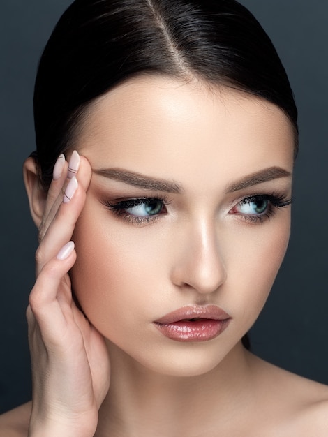 Retrato de uma jovem mulher bonita caucasiana tocando seu rosto. limpeza da pele, cuidados com a pele, conceito de cosmetologia