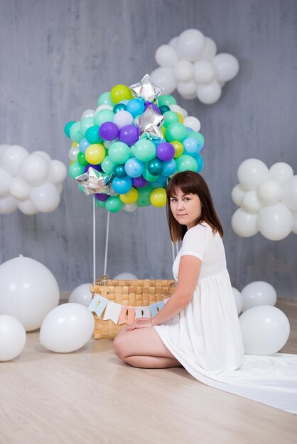 Retrato de uma jovem mulher bonita com balão de ar colorido e nuvens brancas
