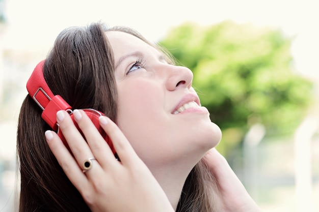 Retrato de uma jovem mulher bonita com fones de ouvido vermelhos, ouvindo música