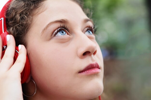 Retrato de uma jovem mulher bonita com fones de ouvido vermelhos, ouvindo música