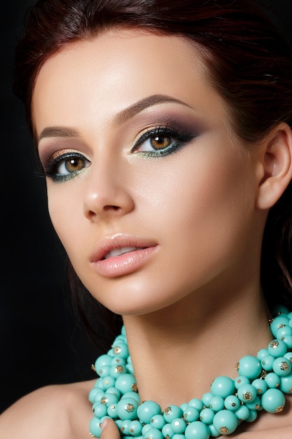 Foto retrato de uma jovem mulher bonita com maquiagem de noite usando colar azul