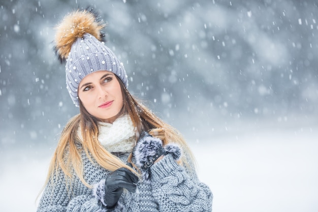 Retrato de uma jovem mulher bonita com roupas de inverno e forte nevando.