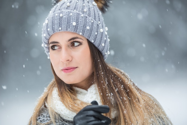 Retrato de uma jovem mulher bonita com roupas de inverno e forte nevando.