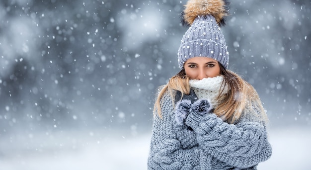 Retrato de uma jovem mulher bonita com roupas de inverno e forte nevando.