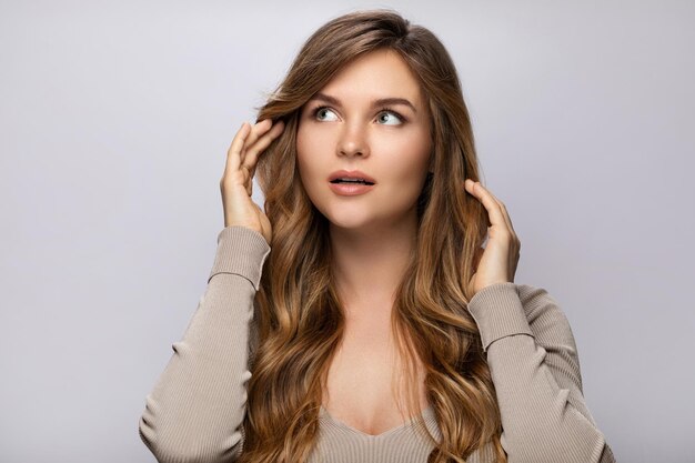 Retrato de uma jovem mulher bonita com um penteado encaracolado em fundo cinza