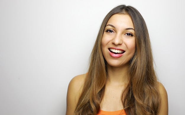 Retrato de uma jovem mulher bonita com uma blusa laranja alegremente sorrindo