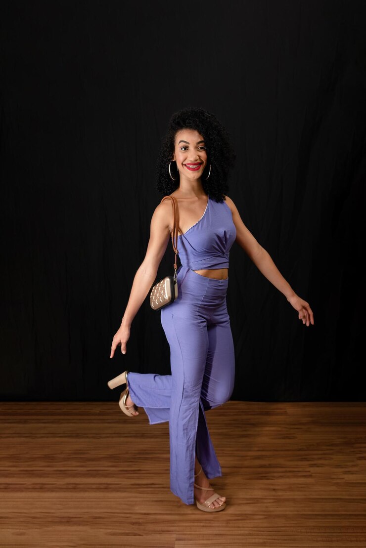 Foto retrato de uma jovem mulher bonita e alegre de pé no estúdio segurando uma bolsa vestindo roupas azuis contra um fundo preto