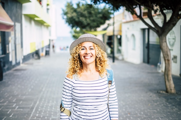 Retrato de uma jovem mulher bonita e encaracolada olhando para a câmera enquanto caminhava na rua descobrindo e viajando por novos lugares