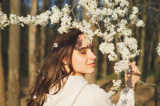 Retrato de uma jovem mulher bonita entre o conceito de primavera de moda e beleza de árvores floridas