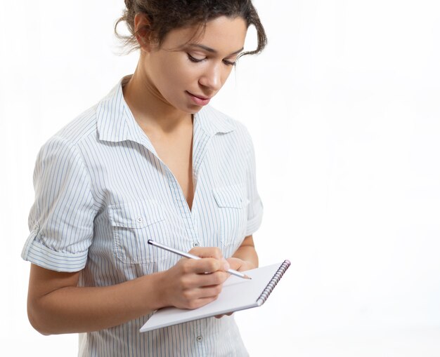 Foto retrato de uma jovem mulher bonita escrevendo a lápis em um caderno