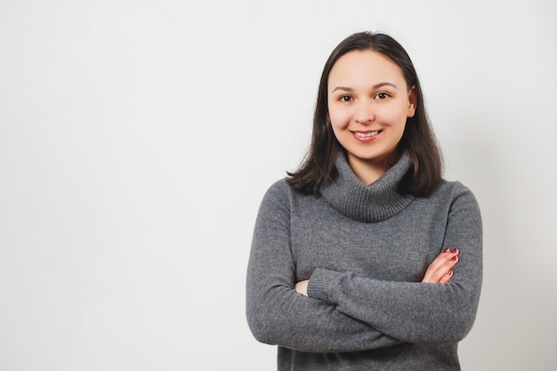 Retrato de uma jovem mulher bonita, mãos dobradas na frente dela, isolado no branco.