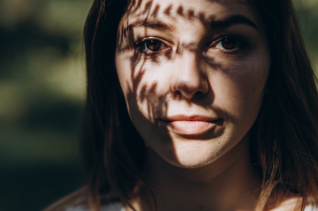 Foto retrato de uma jovem mulher bonita na floresta, na sombra de samambaias no rosto
