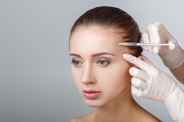 Retrato de uma jovem mulher bonita recebendo injeção plástica de levantamento na testa. Cirurgia plástica. Tratamento Cosmético