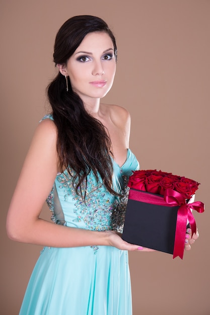 Retrato de uma jovem mulher bonita segurando uma caixa com flores rosas vermelhas
