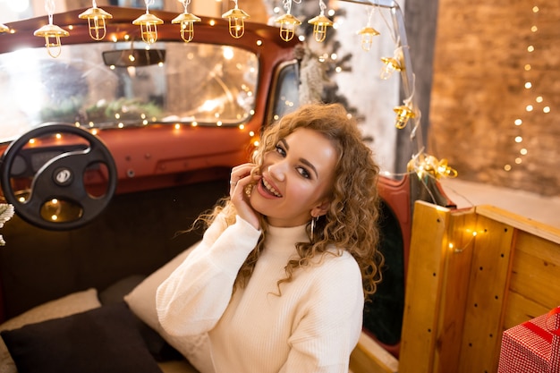 Retrato de uma jovem mulher bonita sentada no carro esperando o natal