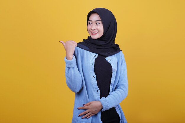 Retrato de uma jovem mulher bonita usando hijab, sorrindo com alegria e parecendo feliz, sentindo-se despreocupada e positiva com os dois polegares para cima