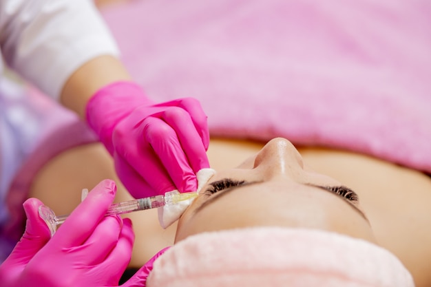 Foto retrato de uma jovem mulher branca recebendo injeção cosmética de botox na testa