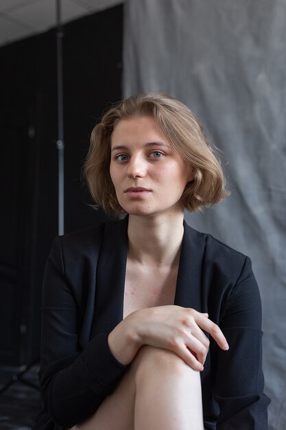 Retrato de uma jovem mulher caucasiana com cabelo curto, posando com um paletó preto