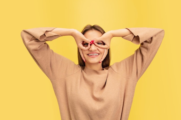 Retrato de uma jovem mulher caucasiana com emoções brilhantes, isolada no fundo amarelo do estúdio