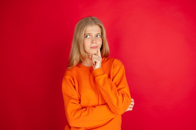 Retrato de uma jovem mulher caucasiana com emoções brilhantes, isolada no fundo vermelho do estúdio