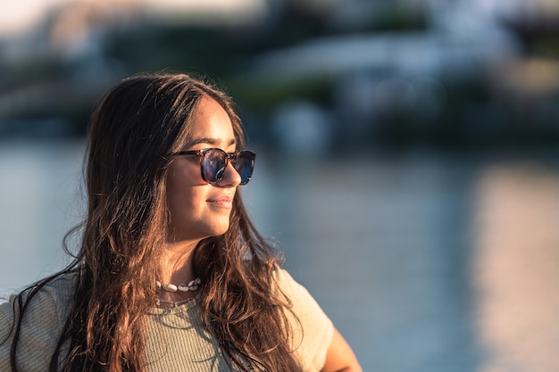 Retrato de uma jovem mulher caucasiana com óculos de sol de frente para o pôr do sol ao ar livre