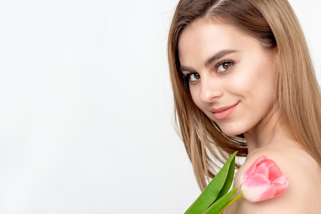 Retrato de uma jovem mulher caucasiana feliz com uma tulipa rosa contra um fundo branco com espaço de cópia