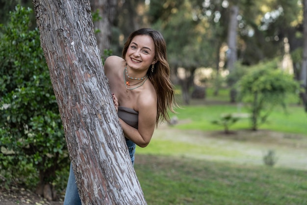 Retrato de uma jovem mulher caucasiana posando atrás de uma árvore