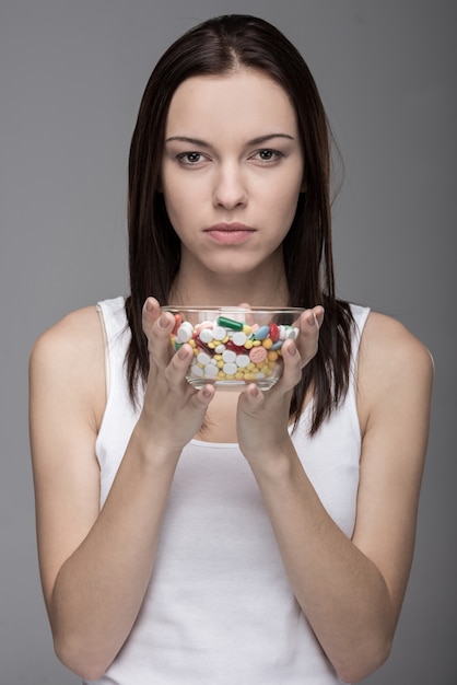 Foto retrato de uma jovem mulher com comprimidos em um frasco de vidro.