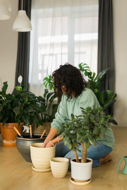 Foto retrato de uma jovem mulher com uma planta em vaso em casa