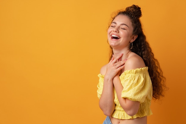 Foto retrato de uma jovem mulher de cabelos encaracolados contra um fundo amarelo