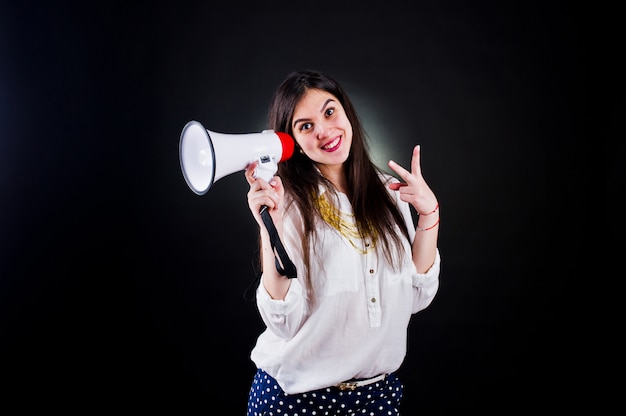 Retrato de uma jovem mulher de calça azul e blusa branca, posando com megafone