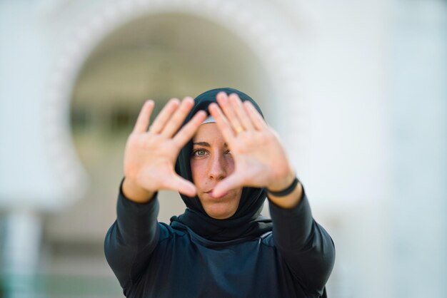 Foto retrato de uma jovem mulher de hijab fazendo gestos ao ar livre