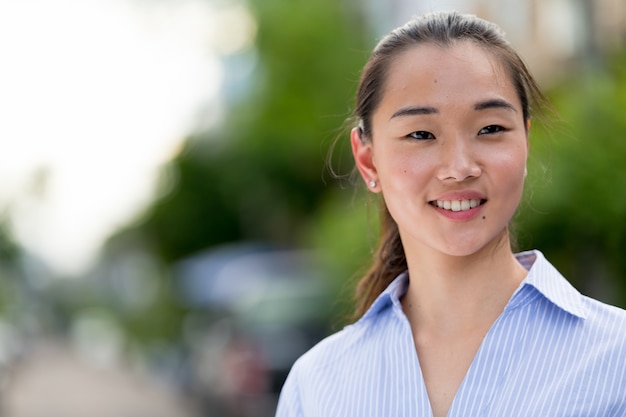 Retrato de uma jovem mulher de negócios asiática bonita na rua ao ar livre