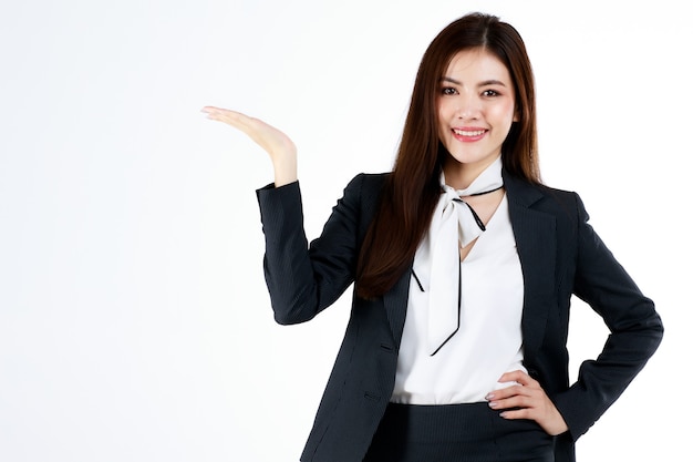 Retrato de uma jovem mulher de negócios asiática em terno formal posando e mostrar a mão no espaço em branco para apresentar ou demonstrar bens ou produtos em gesto de publicidade, estúdio filmado em fundo branco.