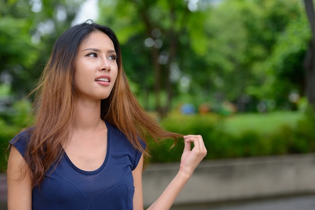 Retrato de uma jovem mulher de negócios asiática relaxando no parque ao ar livre