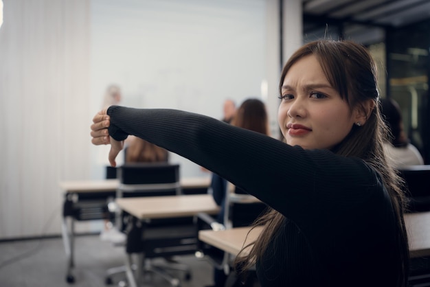 Retrato de uma jovem mulher de negócios no escritório Uma jovem mulher dá o polegar para baixo