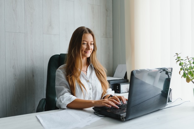 Retrato de uma jovem mulher de negócios usando laptop no escritório