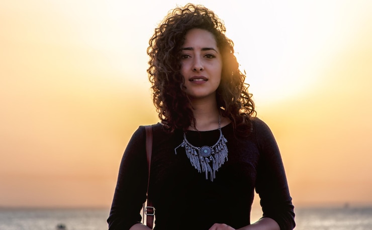 Foto retrato de uma jovem mulher de pé na praia contra o céu durante o pôr do sol