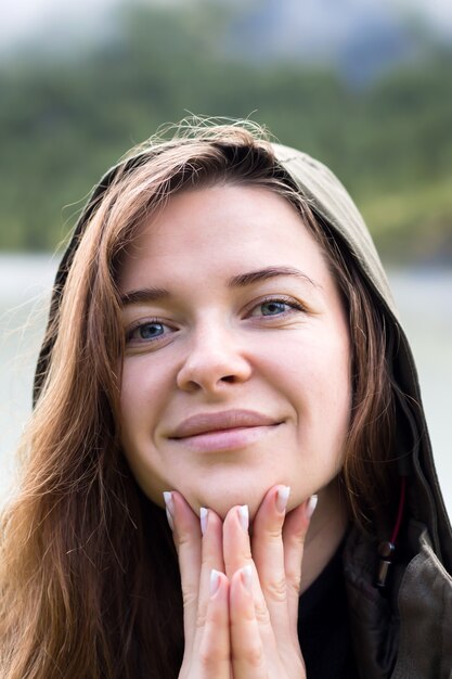 Retrato de uma jovem mulher em hoo traz os dedos aos lábios.