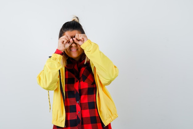 Retrato de uma jovem mulher esfregando os olhos em uma camisa xadrez, jaqueta e olhando de frente com curiosidade