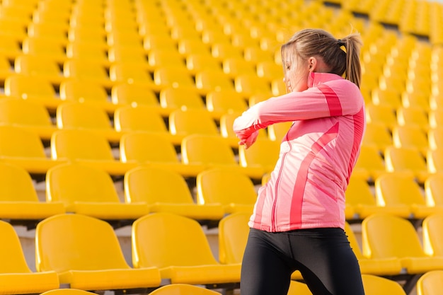 Retrato de uma jovem mulher fitness aquecendo no estádio