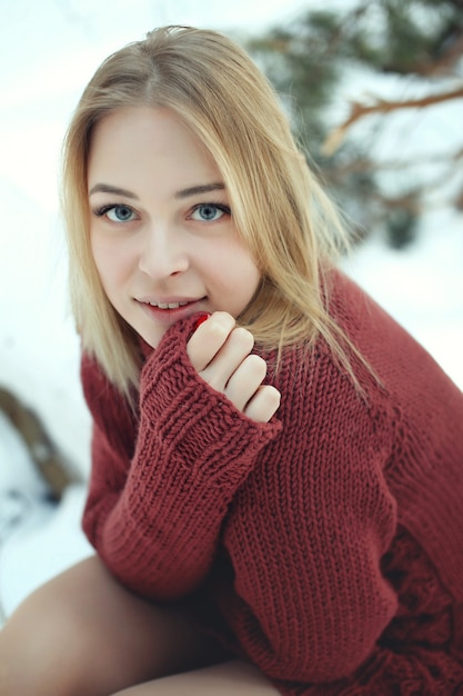 Retrato de uma jovem mulher loira bonita com suéter posando em um dia ensolarado de inverno