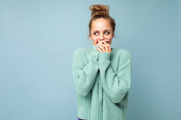 Retrato de uma jovem mulher loira encantadora e encantadora com emoções sinceras, vestindo um suéter azul da moda